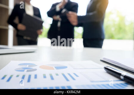 business document in touchpad lying on the desk, office workers discussting meeting in the background Stock Photo