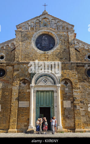 A group of tourists in front of the  Romanesque-Pisan facade of the Cathedral dedicated to the Assumption of the Virgin Mary - Volterra, Tuscany, Ital Stock Photo