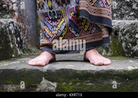 Close up view on man foot in balinese indonesian sarong. Stock Photo