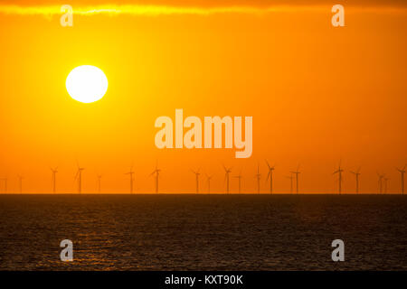 The sun setting behind the Walney Offshore Wind Farm taken from Walney Island, Cumbria, UK. Stock Photo