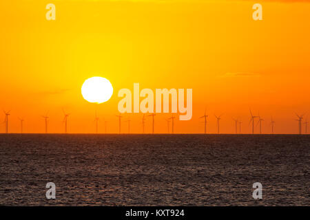 The sun setting behind the Walney Offshore Wind Farm taken from Walney Island, Cumbria, UK. Stock Photo