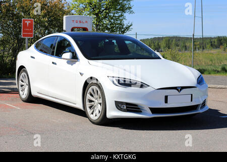 PAIMIO, FINLAND - JUNE 3, 2017: White Tesla Model S luxury sedan with new design on the vehicle exterior is being charged at Tesla Supercharger Statio Stock Photo