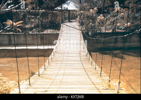 Wire hanging bridge with wooden pathway in Thailand. Stock Photo