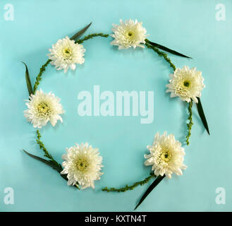 Flower round frame wreath made of white flowers on blue background.  Flat lay, top view Stock Photo