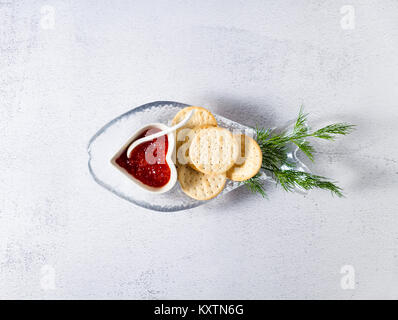 a saucer with red caviar and a cracker for a snack and fresh dill in a plate in the shape of fish . healthy food with Omega-3 Stock Photo