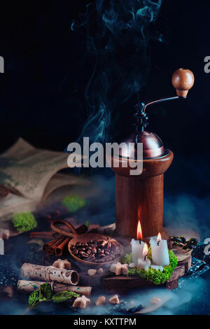 Vintage coffee grinder with coffee beans, star0shaped sugar, and burning candles. Magical still life with open book and copy space. Alternative coffee Stock Photo