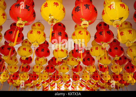 A lot of red and yellow Chinese paper  lanterns hanging on the ceiling of a praying chamber in a Chinese temple during Chinese New Year. Stock Photo