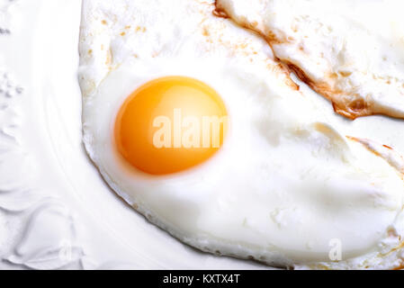 One egg baked and dressed on white plate in close-up Stock Photo