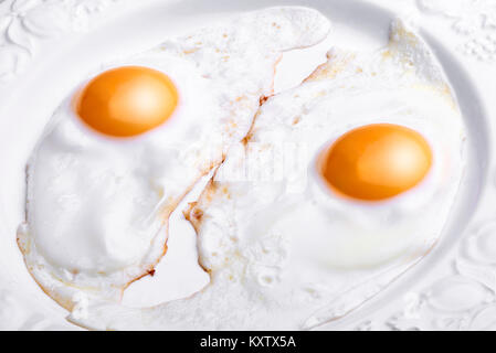 Two eggs baked and dressed isolated on white plate in close-up Stock Photo