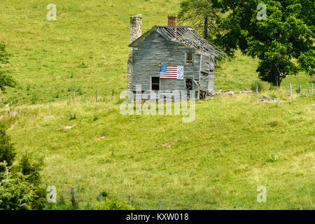 A USA patriotic religious message adorns a dilapidated abandoned farm house in a field. Stock Photo