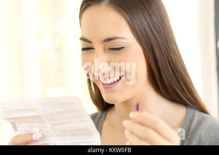 Happy girl holding a painkiller capsule and reading a leaflet at home Stock Photo