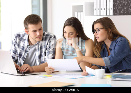 Business team coworking analyzing and commenting reports sitting in a desktop at office Stock Photo