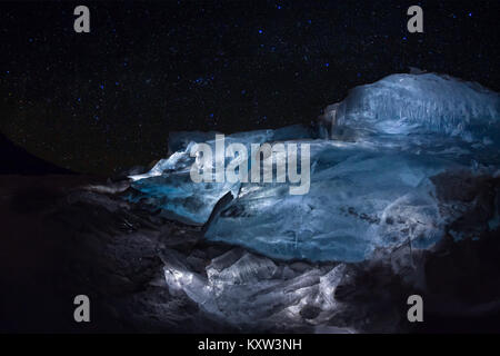 Luminous hummocks of the blue ice of Lake Baikal under the starry sky. Stock Photo