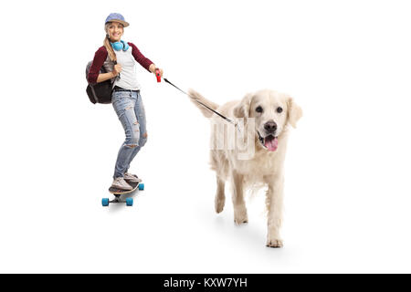 Full length portrait of a female skater with a backpack riding a longboard and walking a dog isolated on white background Stock Photo