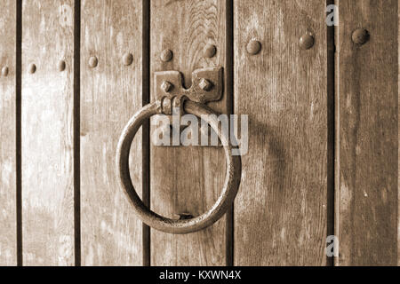 Detail of retro door knocker in the shape of a ring is mounted on a wooden gate. Stock Photo