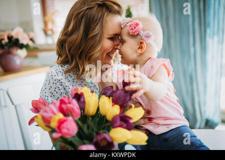 Child daughter congratulates moms and gives her flowers Stock Photo