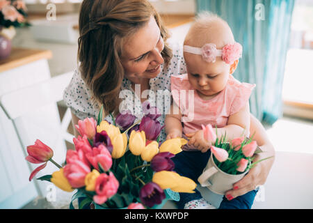 Happy mother and baby making decoration with bouquet of tulips Stock Photo