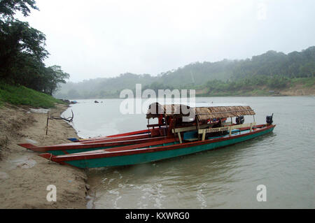 View of a misty and rainy Usumacinta River, natural border between Mexico and Guatemala, from the Mexican side. A wooden canoe waits by the shore. Stock Photo