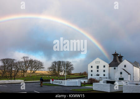 Unusual view outside the front of Lagavulin Whisky Distillery with a couple embracing and a bright rainbow, Isle of Islay, Scotland Stock Photo
