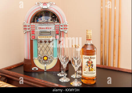 Bottle of Captain Morgan Rum with 5 glasses and a mini juke box with copy space. Stock Photo