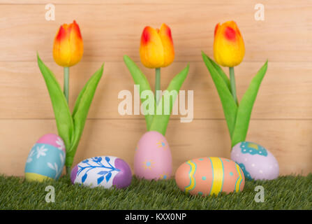 Colorful painted Easter eggs with tulips against a wood background Stock Photo