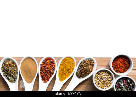 various spices and herbs in spoons snd bowles on wooden tabletop isolated on white Stock Photo