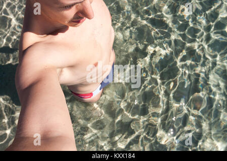 Boy takes a selfie in the clear waters of the Sardinian sea. Alghero, Sardinia. Italy Stock Photo