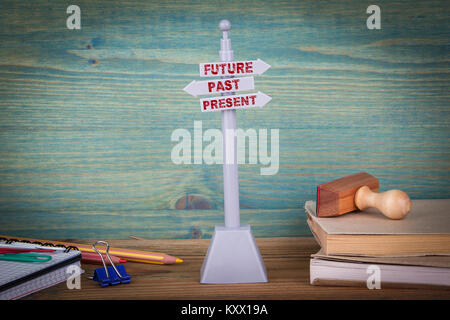 future, past, present. Signpost on wooden table Stock Photo