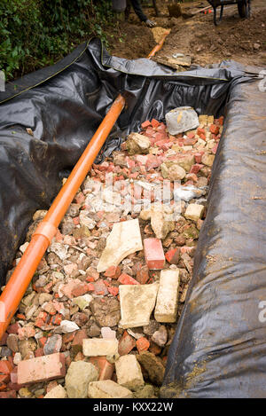 A newly dug pit filled with brick and stone rubble to form a rainwater ...