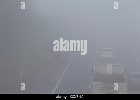 vehicle broken down on hard shoulder as cars pass driving on motorway on a foggy day in the uk Stock Photo