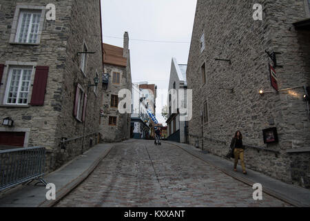 Quebec Canada street person girl walking walk stone streets street old style buildings  cobbles stones shutters on a window windows wood wall ancient Stock Photo