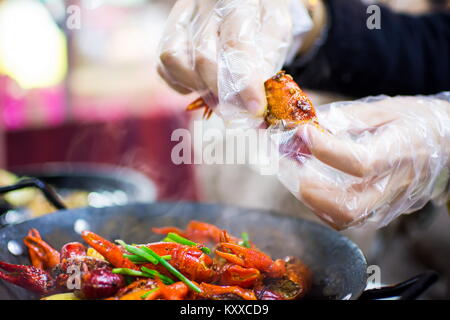 Hands with plastic gloves taking crayfish from spicy crayfish pot on the table Stock Photo