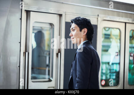 Businessman wearing suit standing at train station platform. Stock Photo