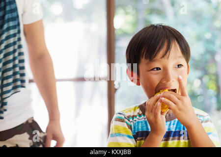 Close up of boy with black hair eating corn on the cob. Stock Photo