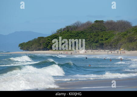 Swimmers in Waves breaking into the bay on the tree fringed beach at high tide Santa Teresa Stock Photo