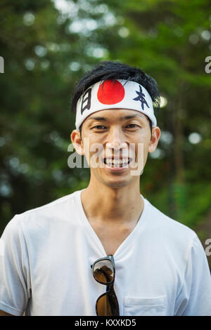 Portrait of man wearing headband  with Japanese flag smiling at camera. Stock Photo