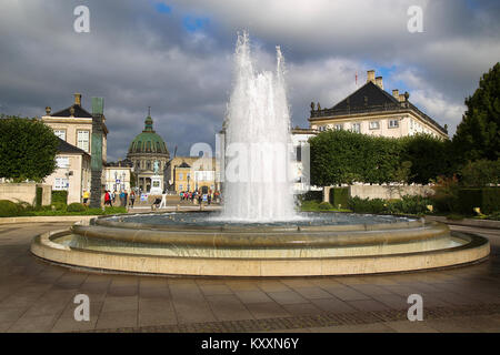 COPENHAGEN, DENMARK - AUGUST 15, 2016: A fountain in the Amalie Garden, with many tourist, in the background is Frederik's Church and Sculpture of Fre Stock Photo