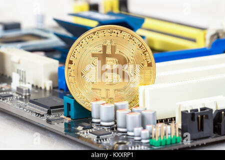 Cryptocurrency golden Bitcoin lying over electronic computer component. Business concept of digital money Stock Photo