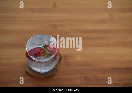 food and drink close up photography image of a glass of ice cube sparkling bubbly water with fresh fruit whole strawberry on wood background space Stock Photo
