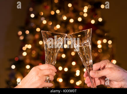 Champagne in two crystal flutes against christmas tree lights Stock Photo