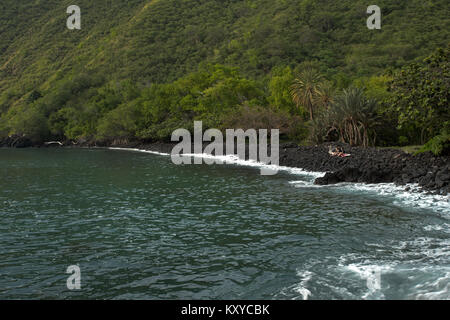 Family friends rocky beach Kealukalua Bay Hawaii. Economy is tourism based. Water and tropical beach recreation and fun. Beautiful clear blue ocean. Stock Photo