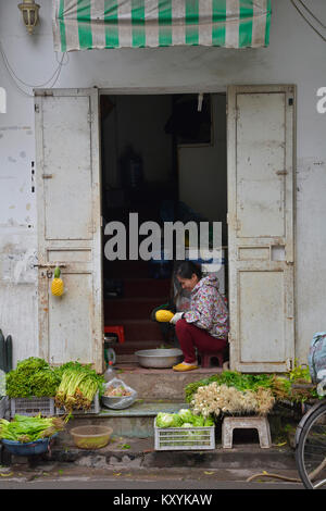 Hanoi, Vietnam - December 14th 2017. A woman prepares pineapples to sell from her home in the historic old quarter of Hanoi Stock Photo