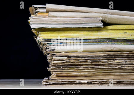 The spines of old books lying on the stack. Books stacked on an old table. Black background. Stock Photo