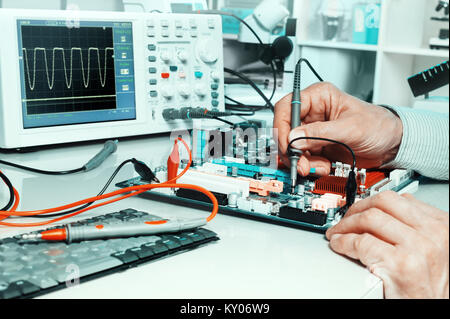 Tech tests electronic equipment in service centre Stock Photo