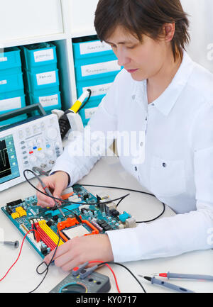 Senior female tech repairs electronic equipment Stock Photo
