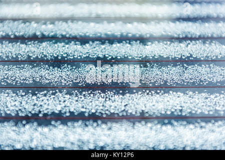 Macro closeup of melting frost snow ice crystals dew rain drops on window glass of car surface showing pattern, texture and bokeh Stock Photo