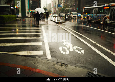 A rainy crosswalk in the streets of Taipei also has a lane for bicycles. Stock Photo