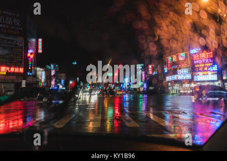 Rainwater on a windshield blurs neon lights and LED signs causing interesting bokeh Stock Photo