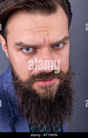 Serious man with gray beard and mustache in winter hat. Looks into ...