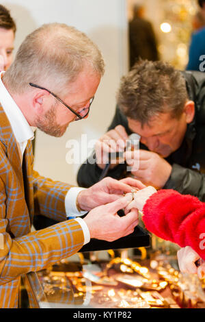 The Art Antiques & Interiors Fair, London, UK. A stallholder tries a diamond ring on the finger of a browser. Stock Photo